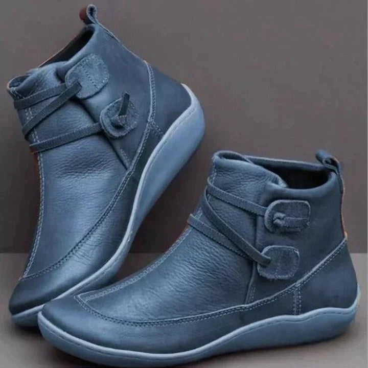 Blue ankle boots shown from the side and three-quarter rear views, featuring adjustable side straps, visible stitching, rear pull tabs, and matching soles.