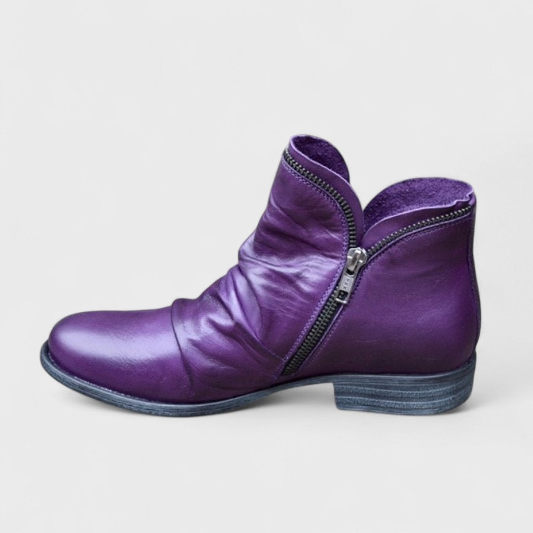 Purple ankle boot shown in side profile with a rounded toe, asymmetric side zip, and low block heel.