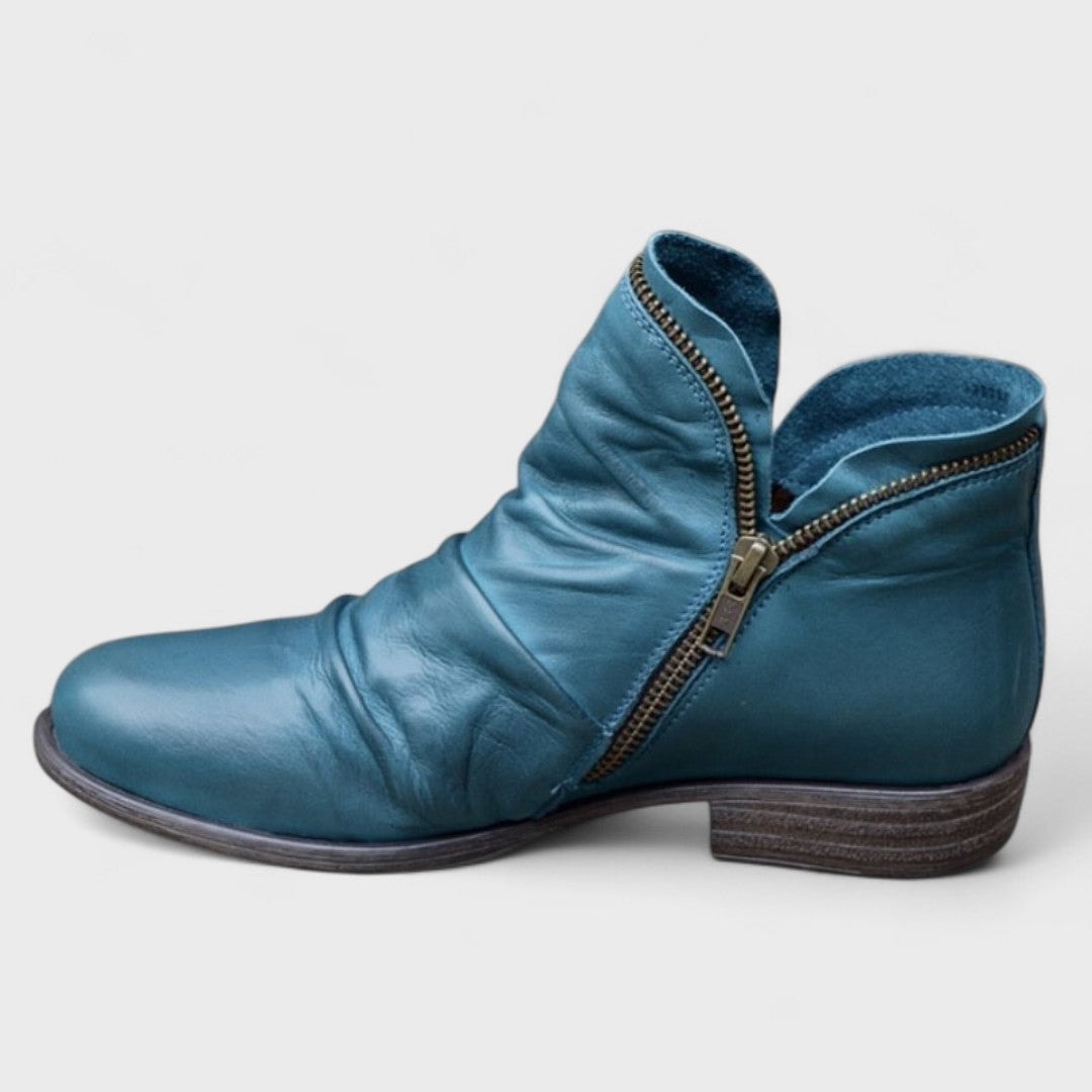 Teal ankle boot in side view with a rounded toe, open ankle opening, and asymmetric zip.