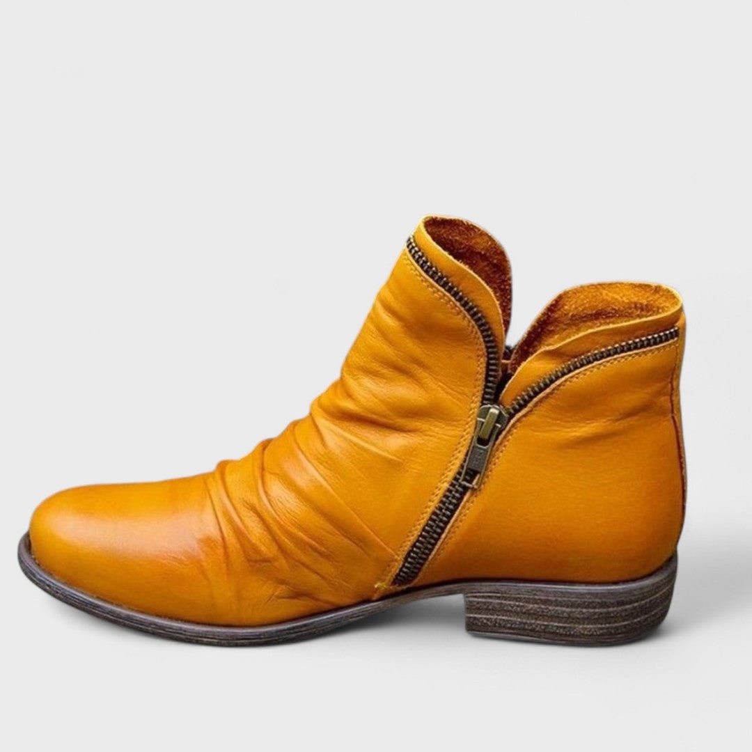Bright yellow ankle boot in profile with a rounded front, asymmetric zip, and low block heel.