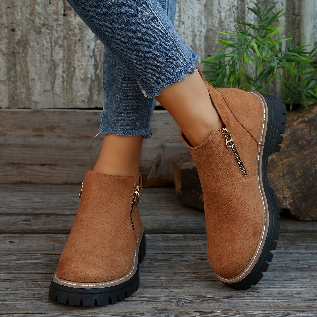 Brown ankle boots worn with cropped jeans, presenting the smooth toe shape, side zip, and rugged sole.