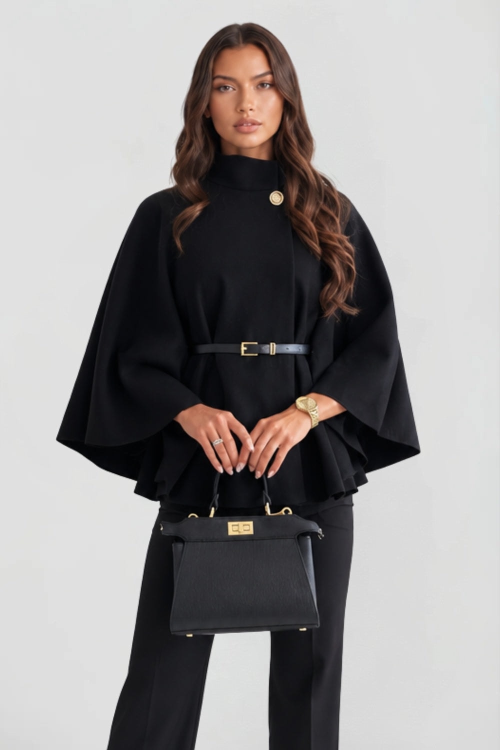 Front view of the black cape jacket with high collar, button closure, wide sleeves, and slim belt.