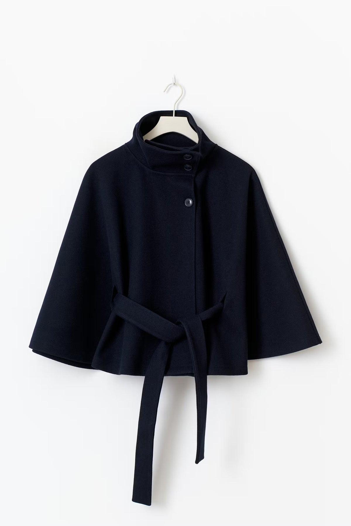Navy cape jacket displayed on a hanger with wide sleeves, stand collar, front buttons, and long waist ties.