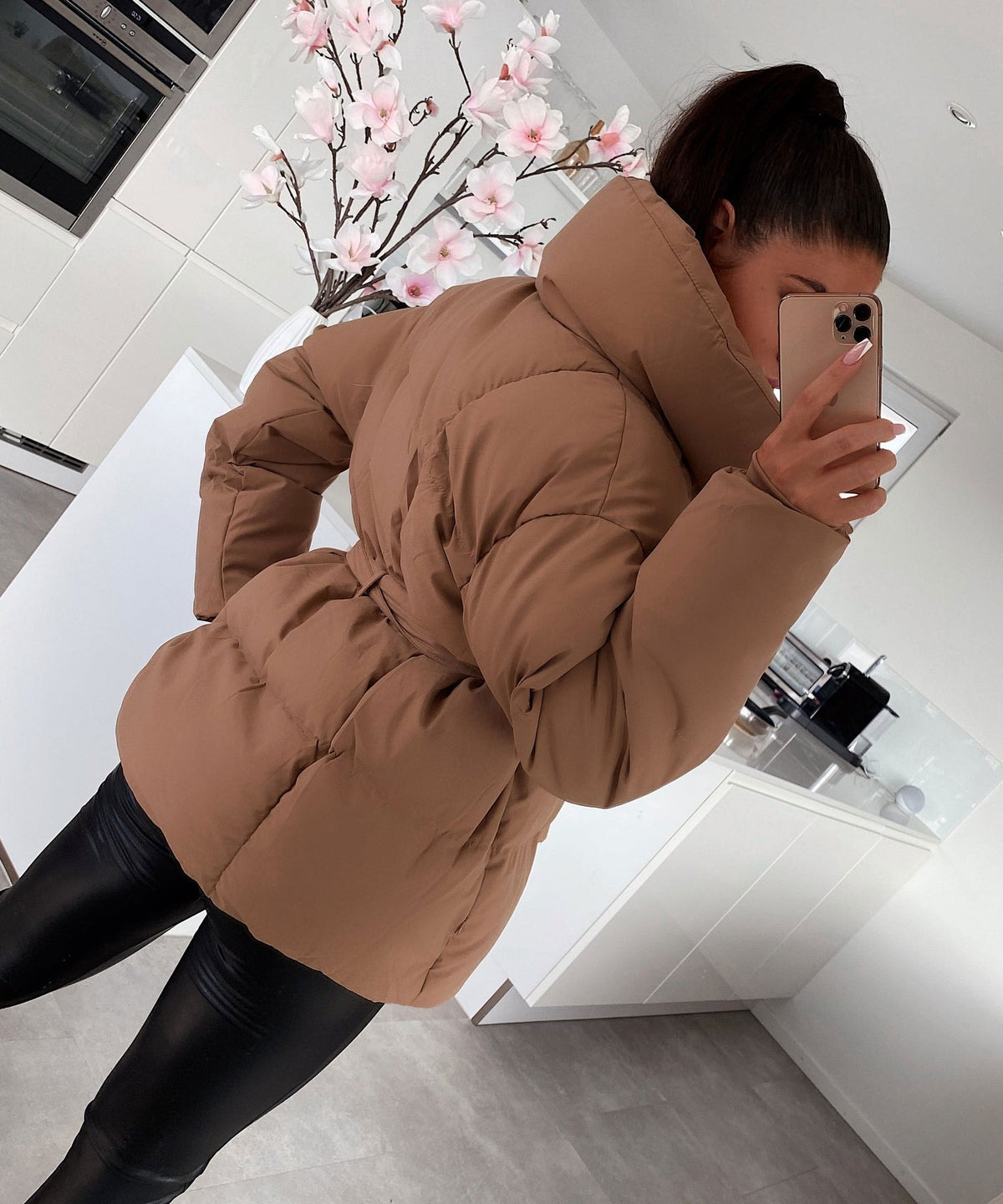 Back and side view of the brown puffer jacket highlighting its padded back, long sleeves, oversized collar, and defined waist.