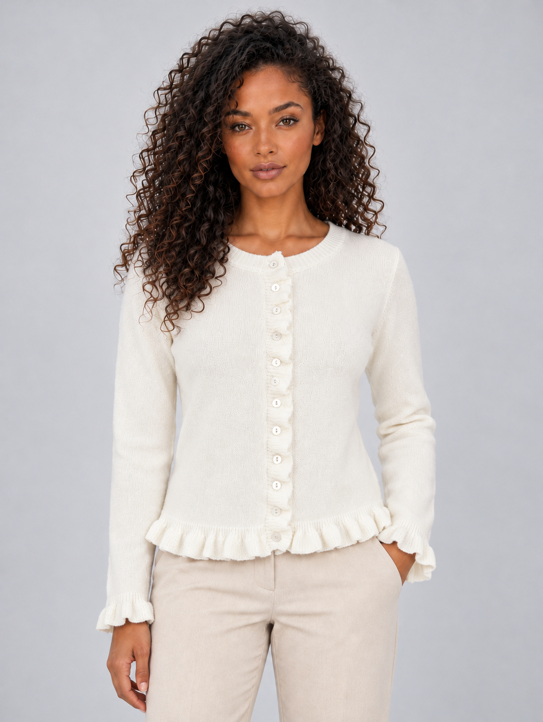 Front view of the cardigan in cream with a round neckline, button closure, fitted sleeves, and prominent ruffle trim.