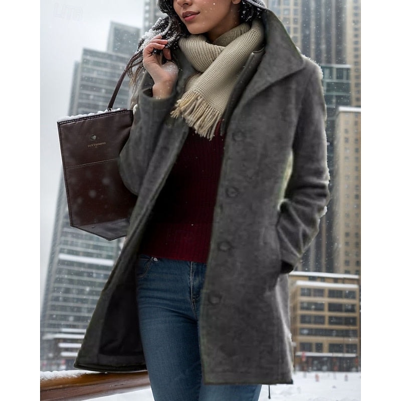Charcoal gray mid-length coat with a notched collar and button front worn in snowy city weather.