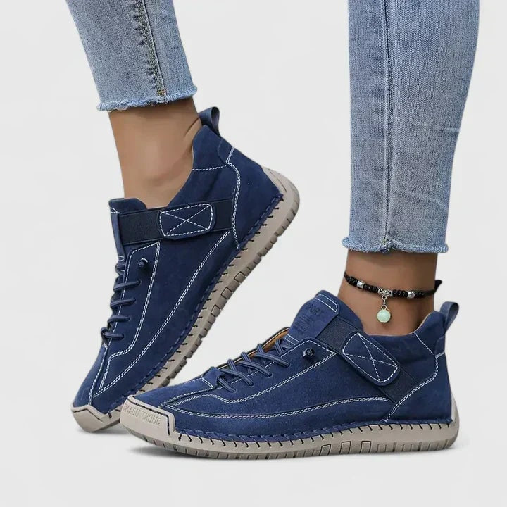 Navy blue sneakers displayed on feet, highlighting the adjustable straps and stitched outsole detail.