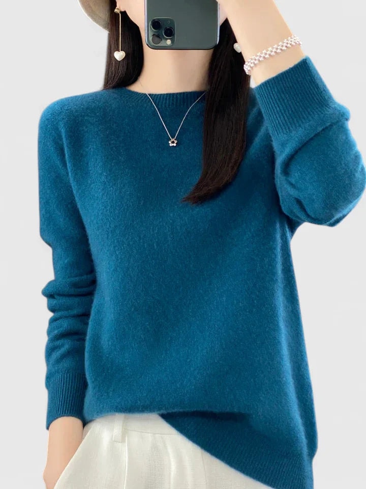 Deep teal crew neck sweater against a plain background, showing its relaxed fit, long sleeves, and ribbed cuffs.