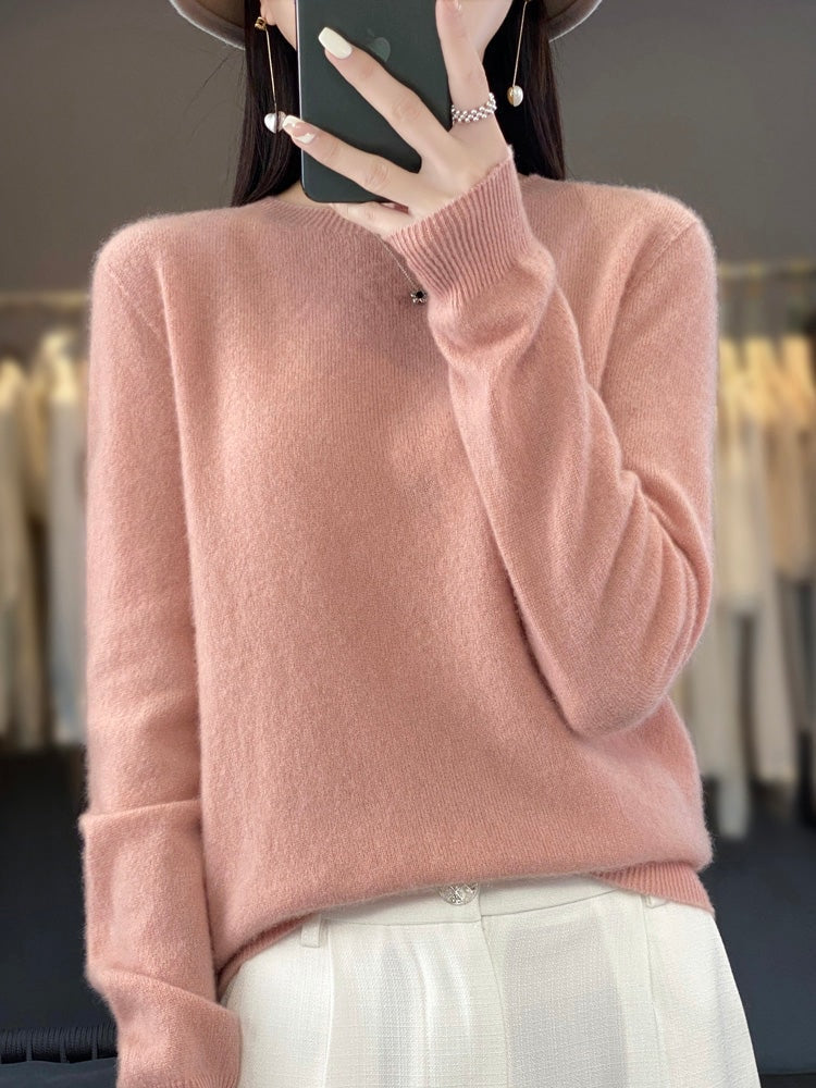 Blush pink crew neck sweater with long sleeves and ribbed cuffs, styled with light trousers.