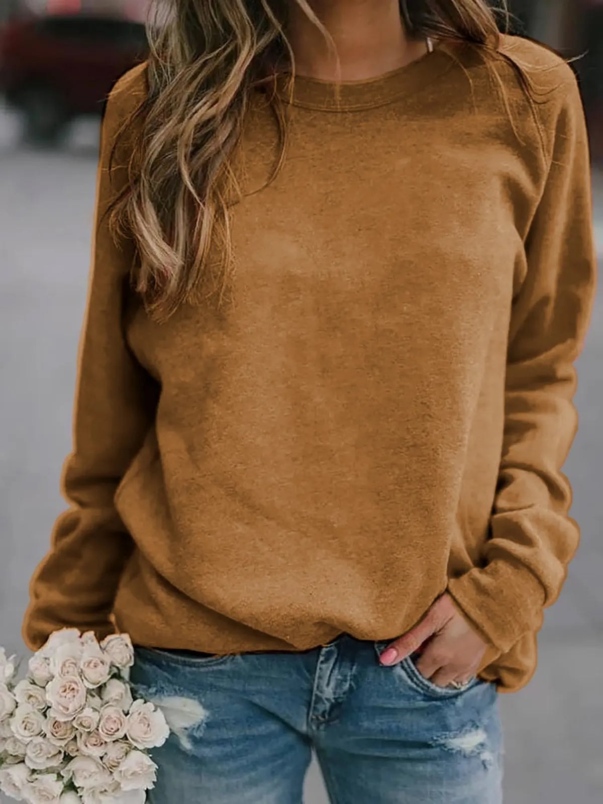Tan crew neck sweatshirt with long raglan sleeves, ribbed cuffs, and a casual fit over jeans.