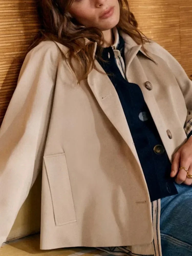 Cropped beige jacket worn open, highlighting the pointed collar and front patch pocket.
