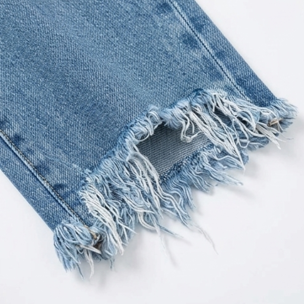 Detailed view of a frayed raw hem with loose threads and a distressed opening near the ankle.