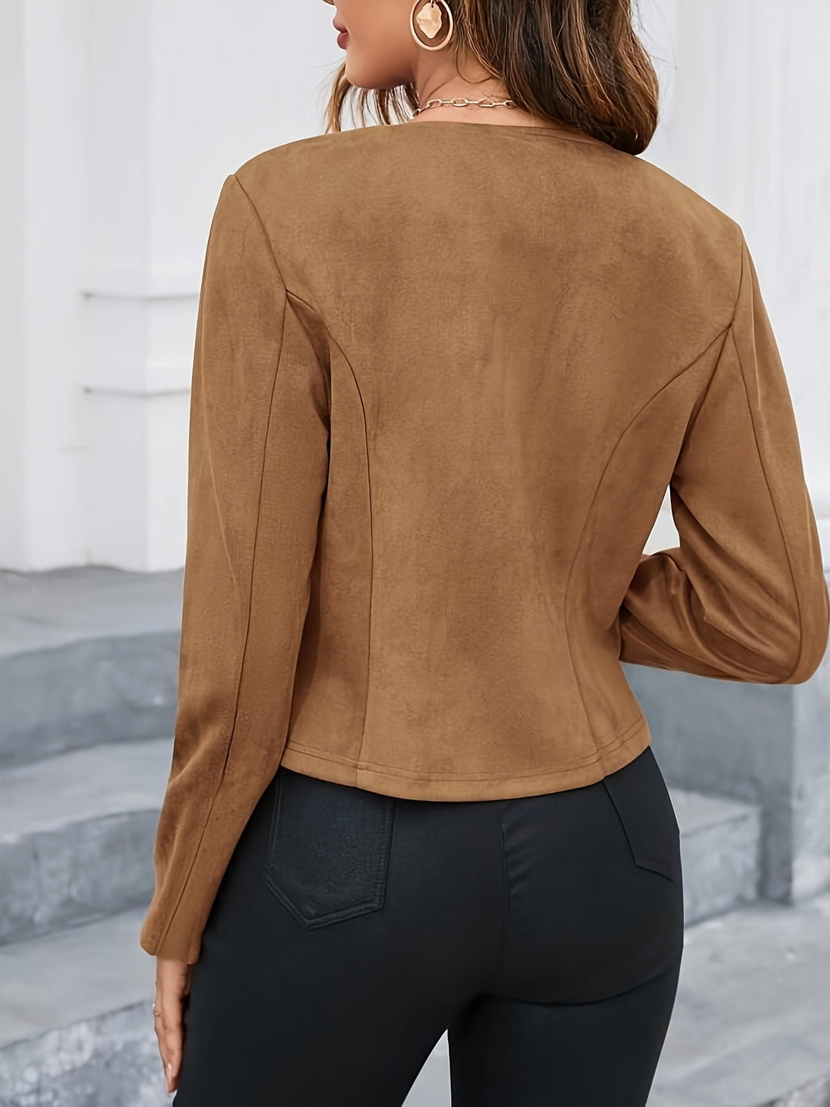 Back view of a brown cropped jacket highlighting its fitted waist and structured seam lines.