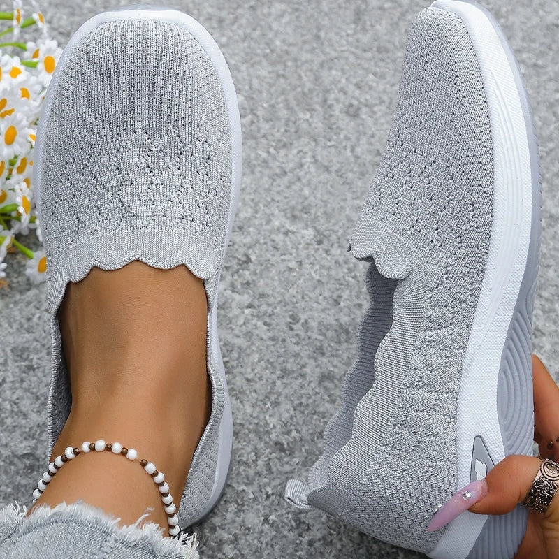 Top and side views of gray knit slip-on shoes displaying the rounded toes and scalloped toplines.