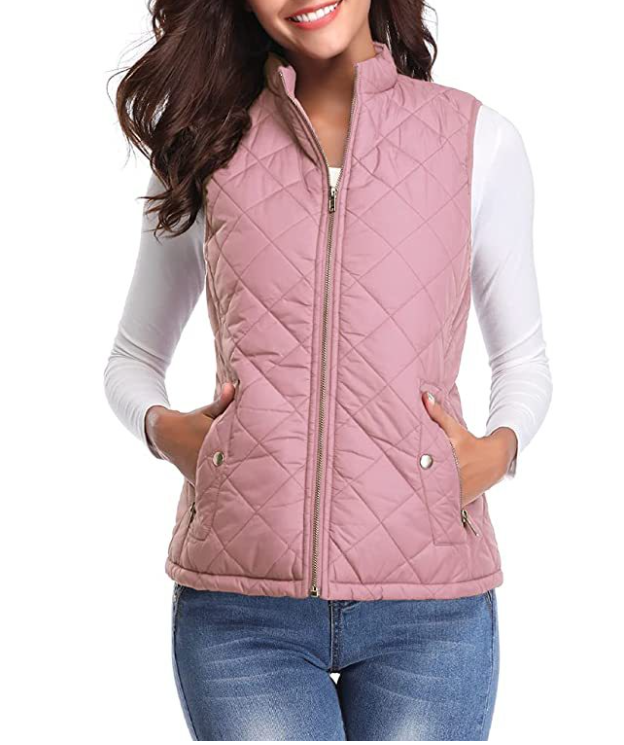Pink diamond-quilted sleeveless vest with stand collar, front zipper, and snap-closure side pockets, worn over a white long-sleeve top.