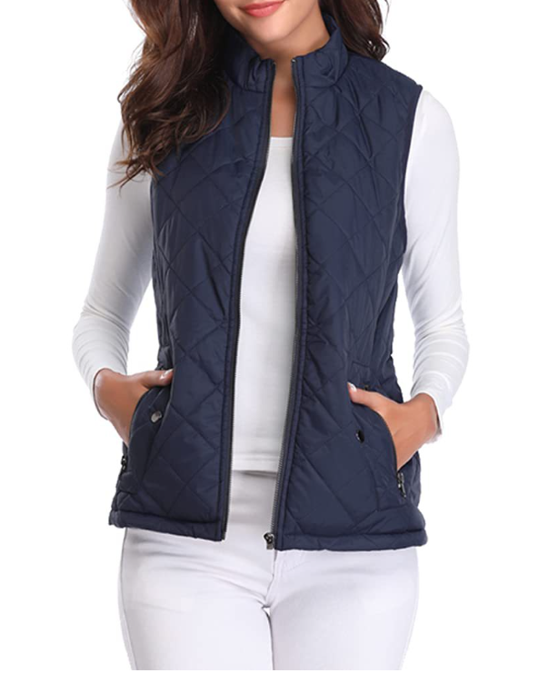 Navy quilted vest worn open over a white top, clearly showing the front zipper and raised collar.