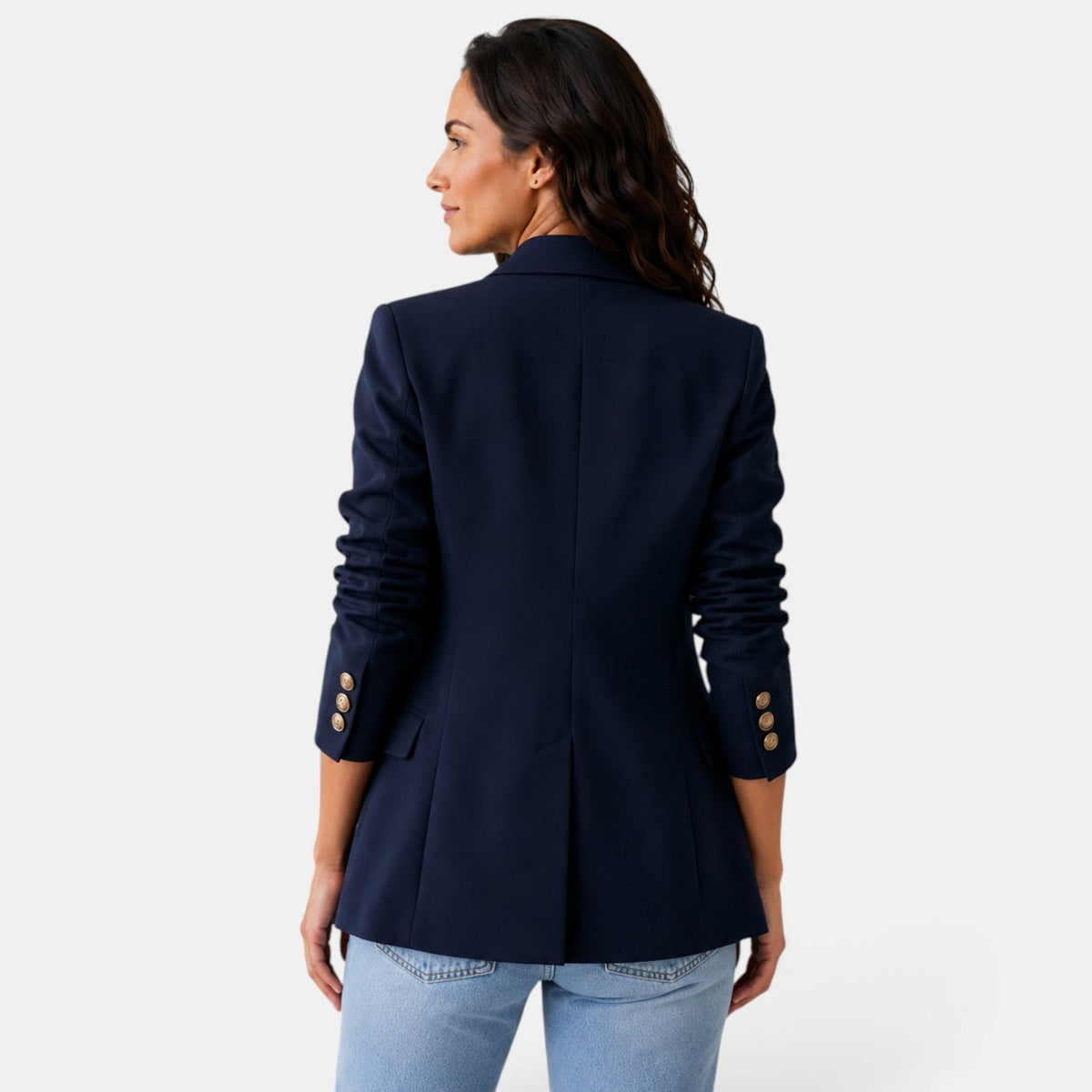 Back view of the navy blazer showing the center seam, shaped waist, straight hem, and buttoned cuffs.