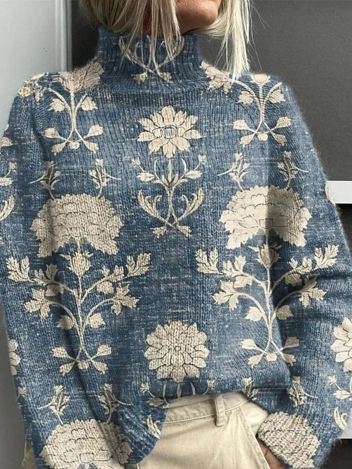 Blue-gray turtleneck sweater decorated with large cream floral and botanical motifs.