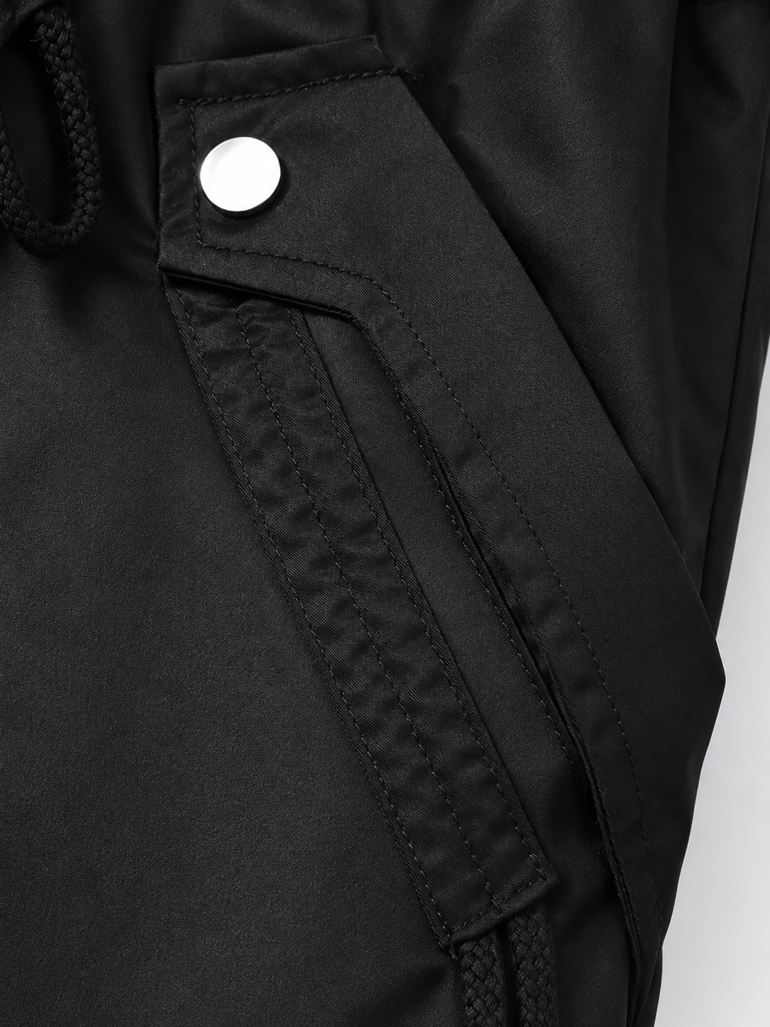 Close-up of the parka's front flap pocket with a press stud and adjustable waist drawstring detail.