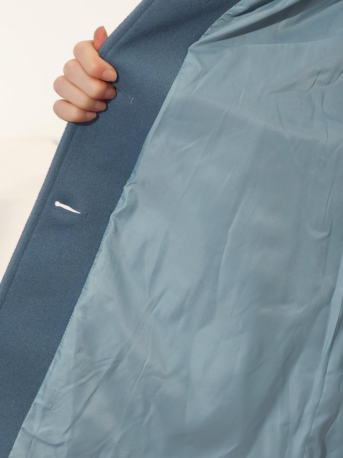 Close-up of the blue coat interior, showing the smooth lining and inside edge of the button-front closure.
