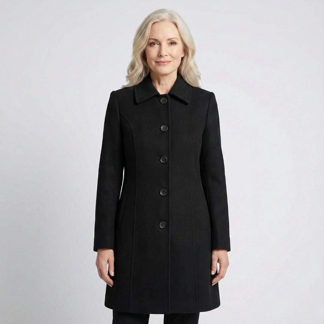 Black coat fully fastened with a neat row of buttons, pointed collar, long sleeves, and softly flared hem.