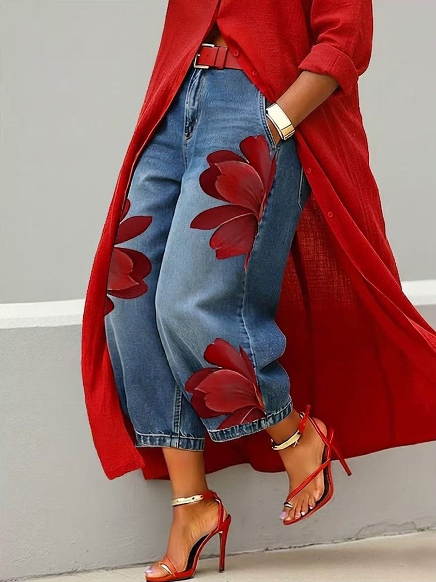Cropped wide-leg blue jeans with oversized red floral prints, styled with a red longline shirt and strappy heels.