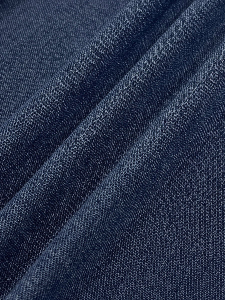 Close-up of the blue denim-like textile surface showing its fine woven texture and diagonal folds.