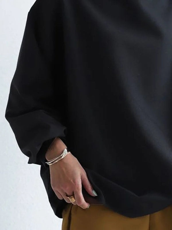 Lower front detail showing the sweatshirt’s longer curved hem and relaxed sleeve ending above the wrist.