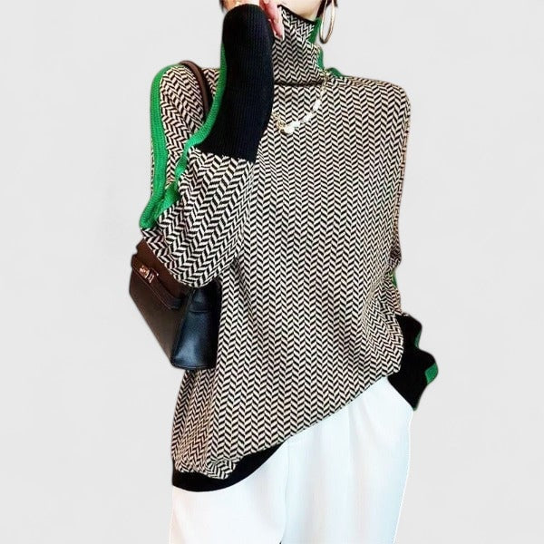 Model wearing the patterned sweater with green-and-black contrast sleeve stripes styled with white trousers.