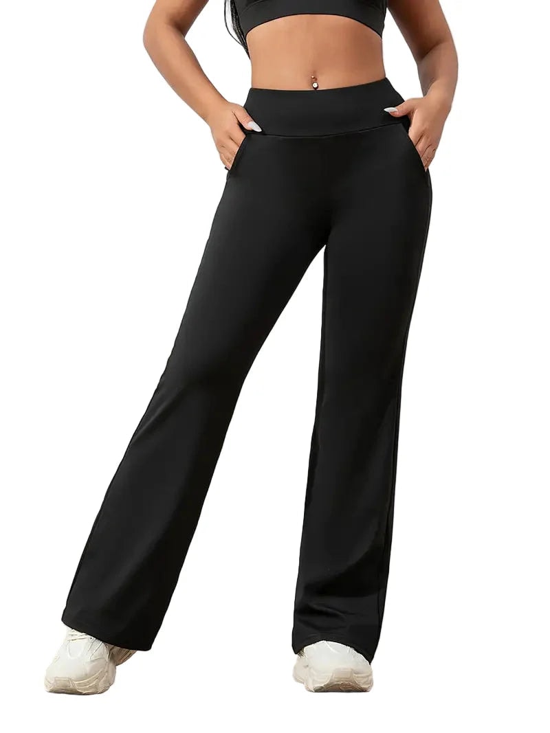 Black high-waisted flared activewear pants shown full length with a wide waistband and white trainers.