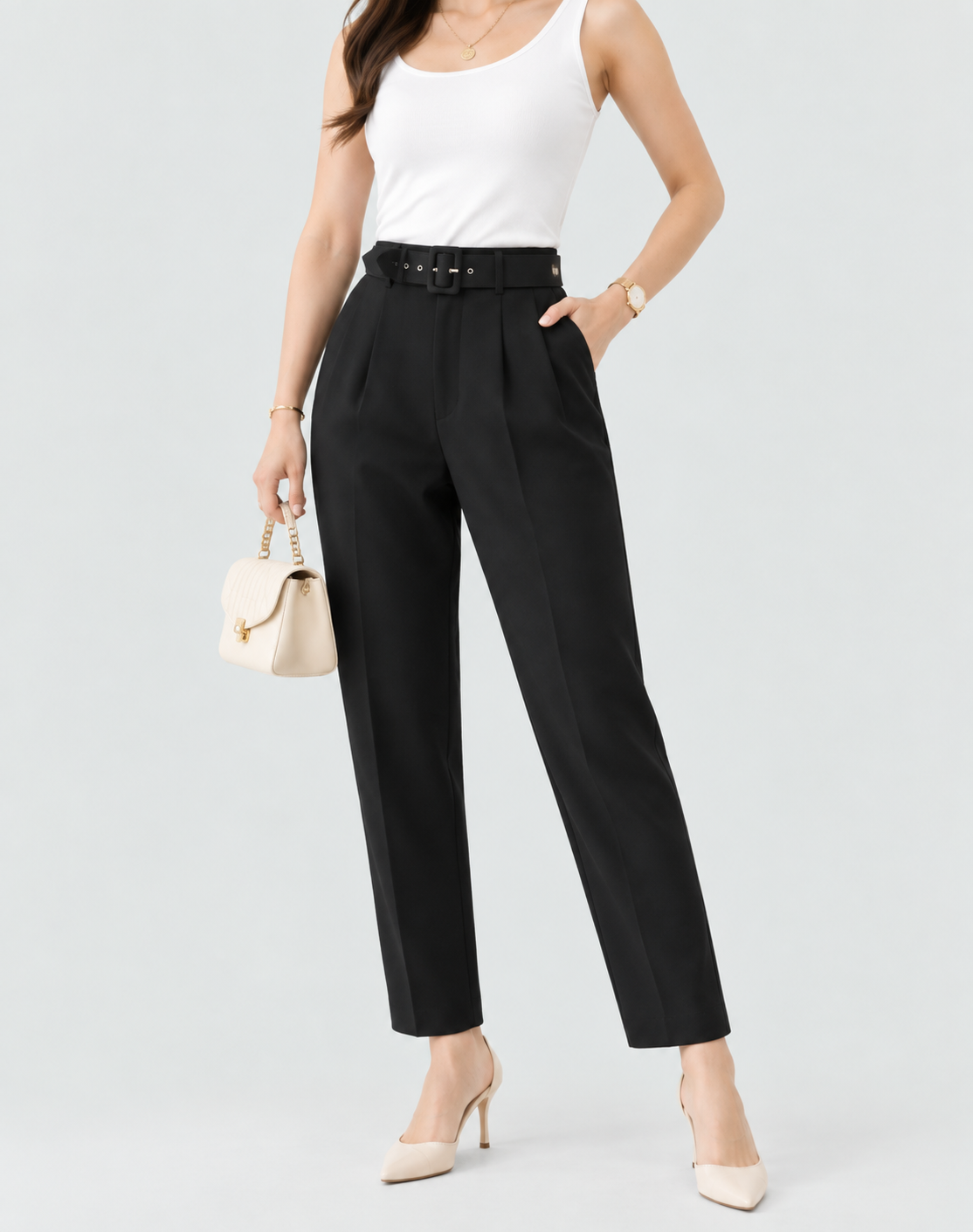 Black high-waisted pleated trousers with tapered ankle-length legs and side pockets, styled with a white tank top, black belt, and pointed heels.
