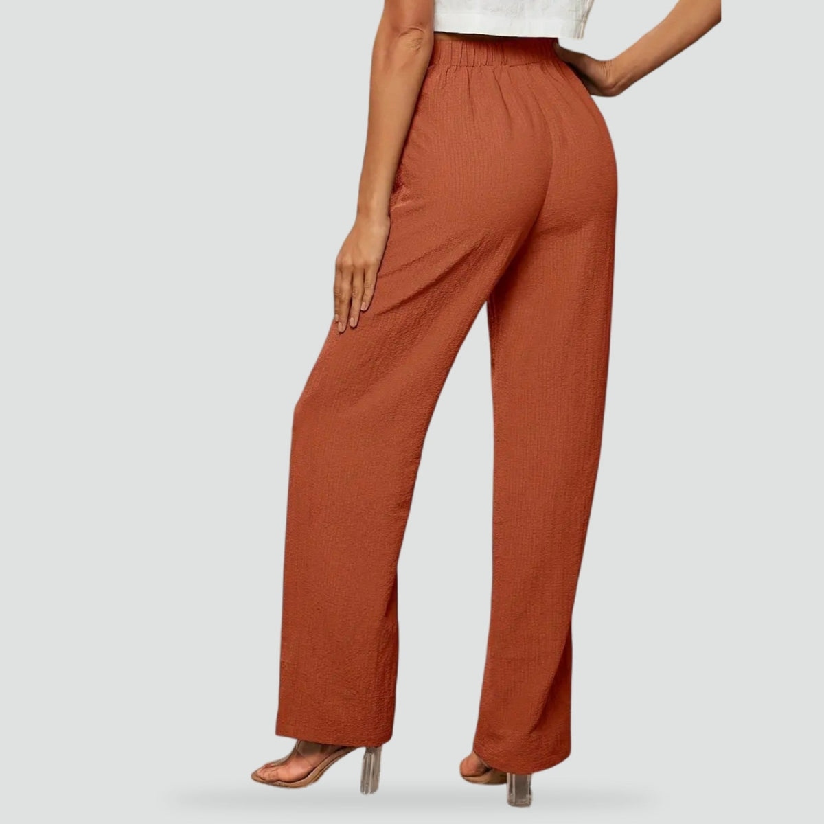 Back view of rust straight-leg trousers, highlighting the gathered elasticated waistband and clean full-length shape.