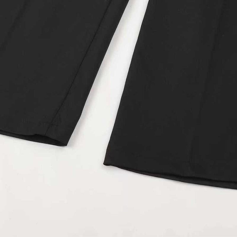 Close-up of black trouser hems showing the clean edge and wide-leg opening.
