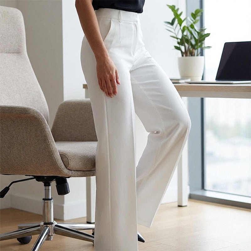 Close view of white high-waisted wide-leg pants showing the waistband, front pleats, and relaxed leg shape.