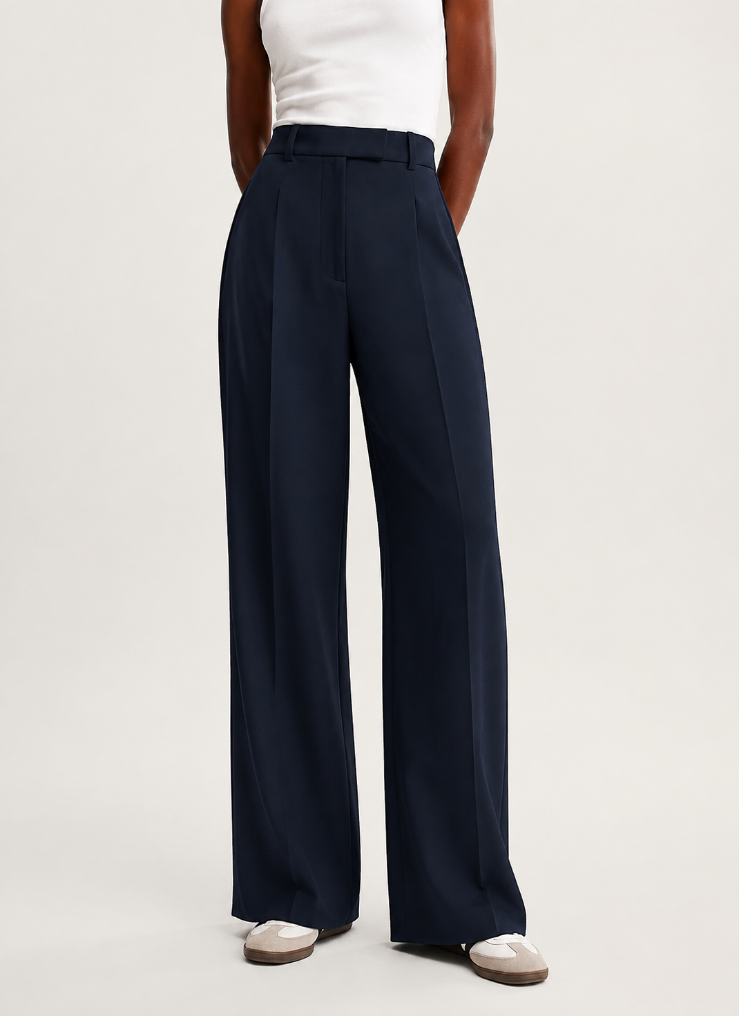Front view of navy wide-leg trousers with both hands in the side pockets and visible front pleats.