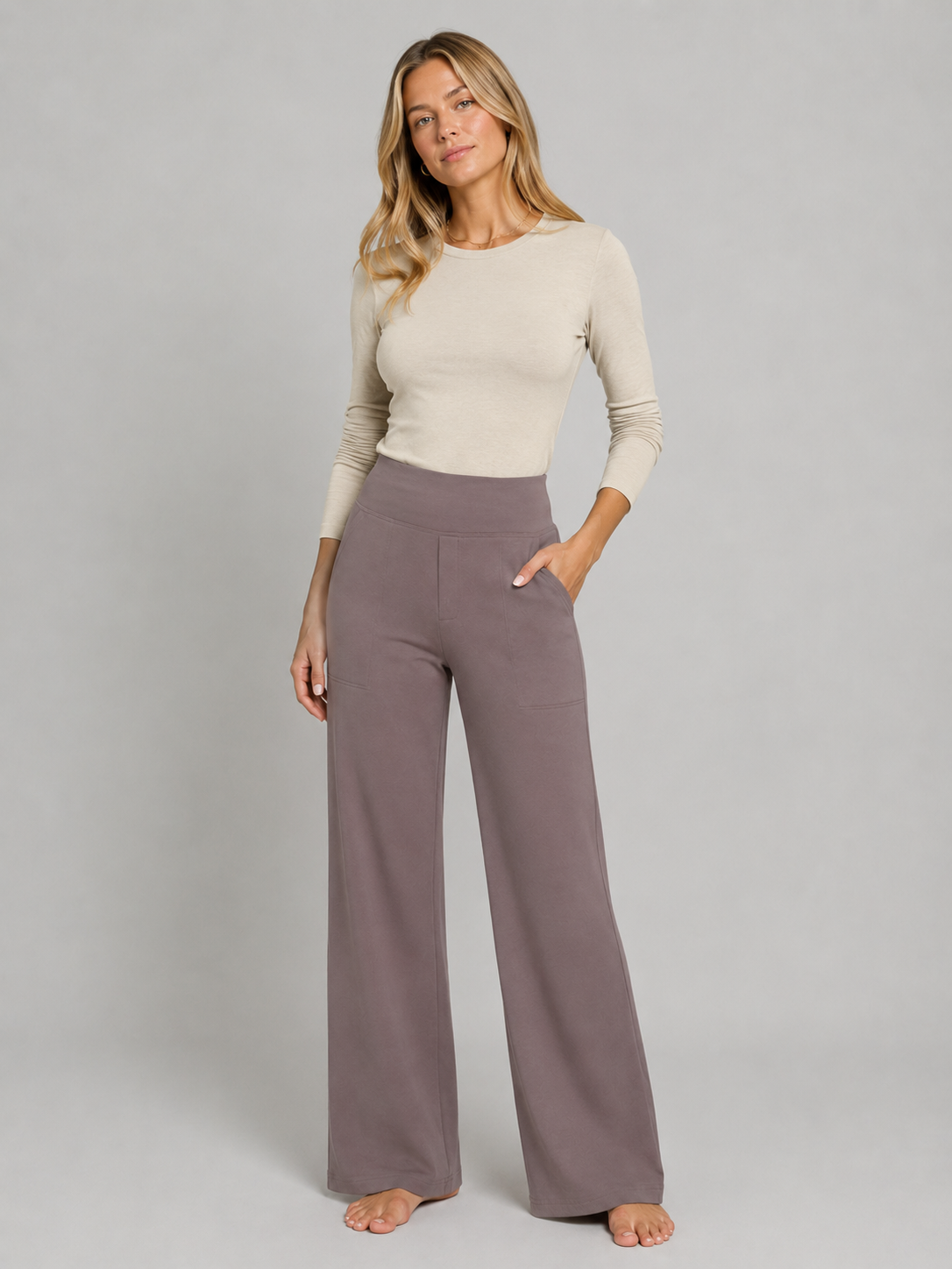 Model wearing taupe high-waisted wide-leg trousers with one hand in a side pocket.