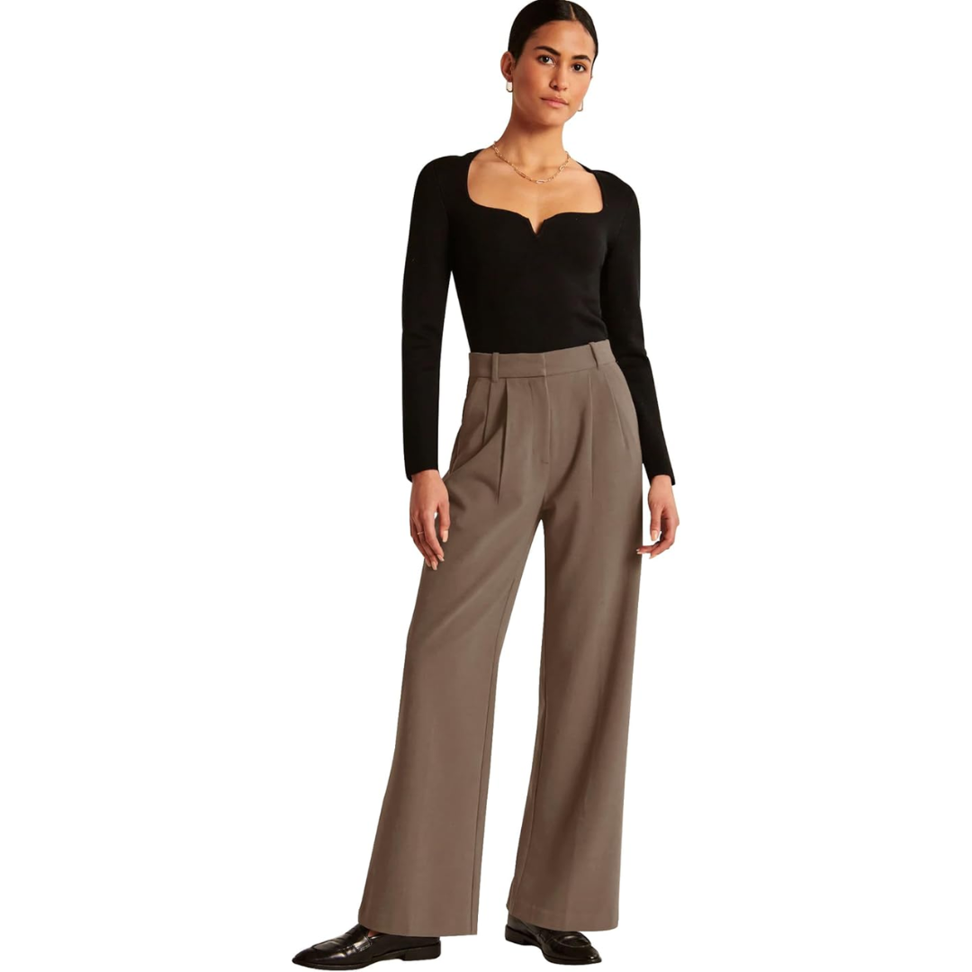 Taupe high-waisted trousers with wide legs and front pleats, styled with a fitted black top and loafers.