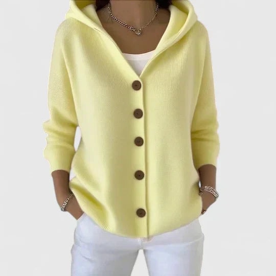 Pale yellow hooded button-front cardigan styled with a white top and white trousers.