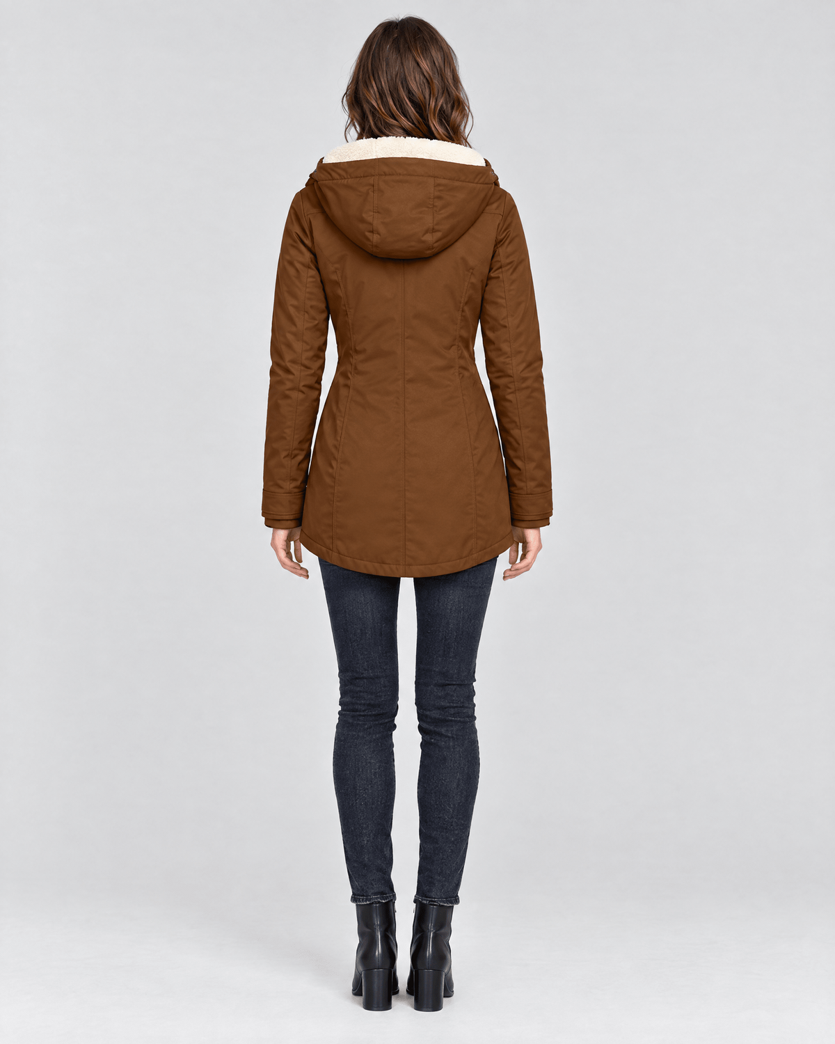 Back view of the brown jacket showing its attached hood, tapered waist, long sleeves, and mid-length curved hem.