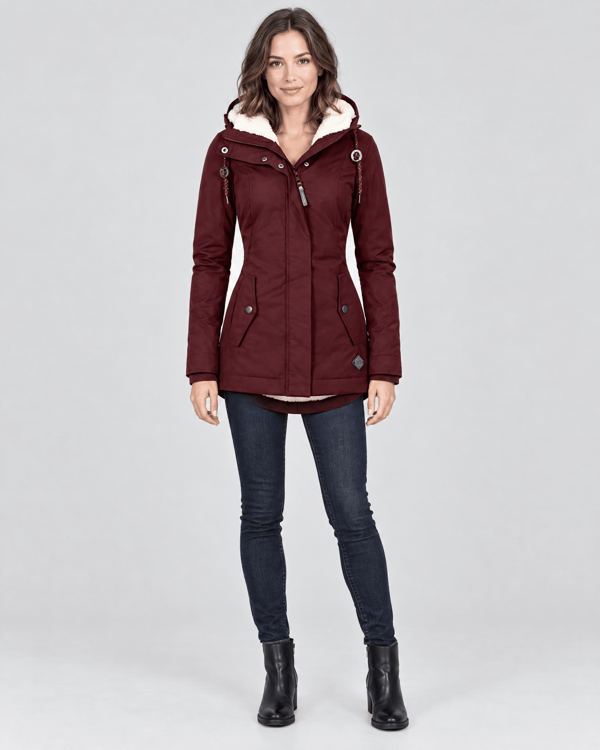 Front view of the burgundy hooded mid-length winter jacket with a lightly fitted silhouette and two angled front pockets.
