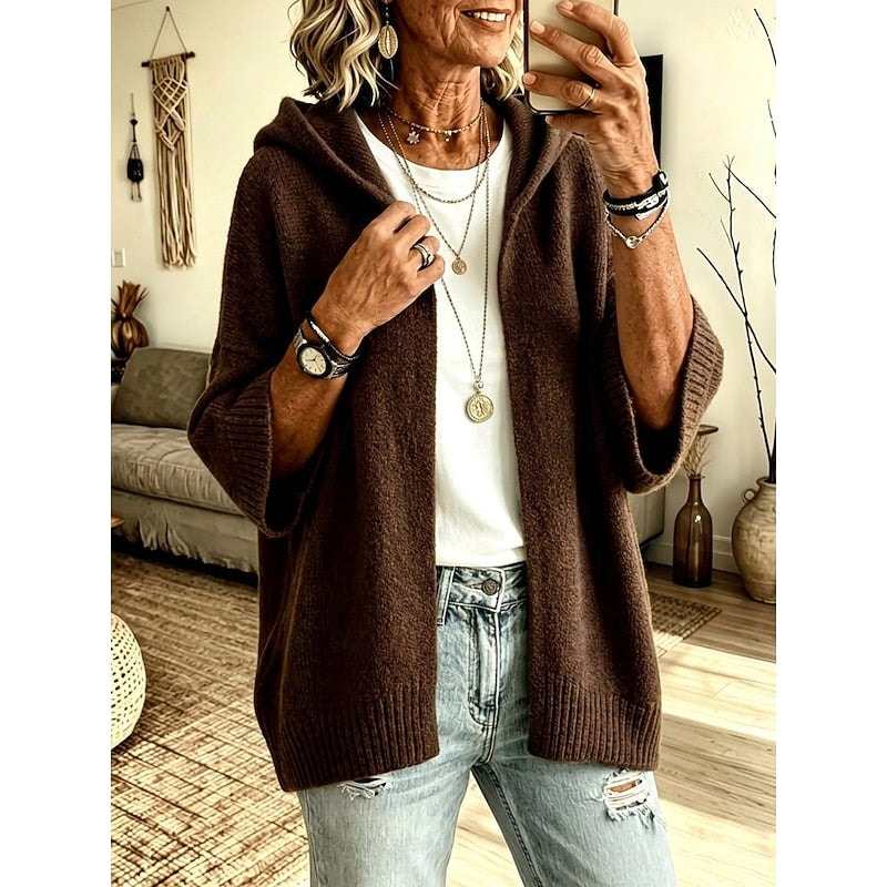 Front view of the brown open-front hooded cardigan, showing its relaxed fit, long ribbed edges, and layered styling over a white top.
