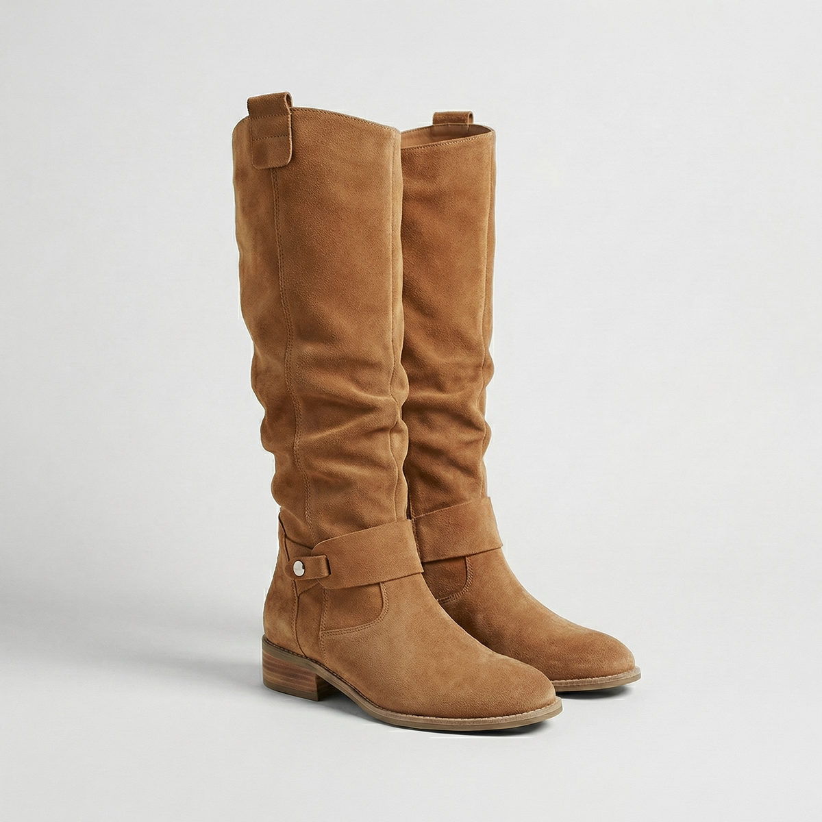 Cognac knee-high boots showing the relaxed gathered shafts, buckle accents and rounded toes from a front three-quarter angle.