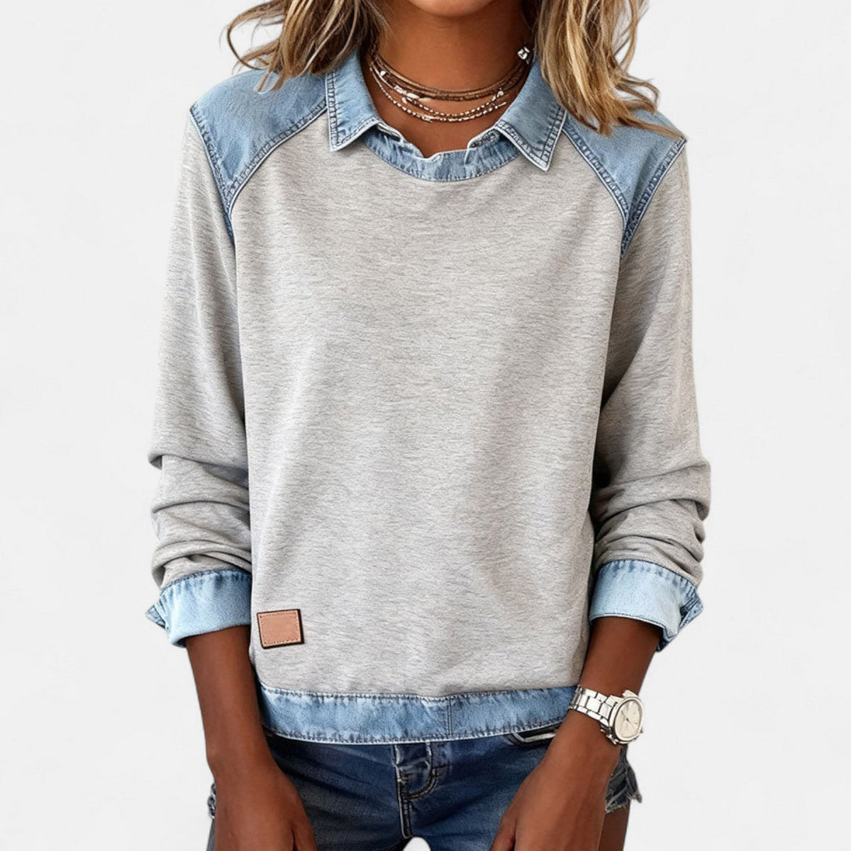 Straight-on view of the gray relaxed-fit sweater with both sleeves pushed up to show the blue cuffs.