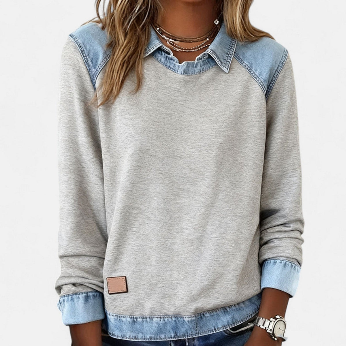 Front view of the gray sweater emphasizing the contrasting blue shoulder panels and broad hem trim.