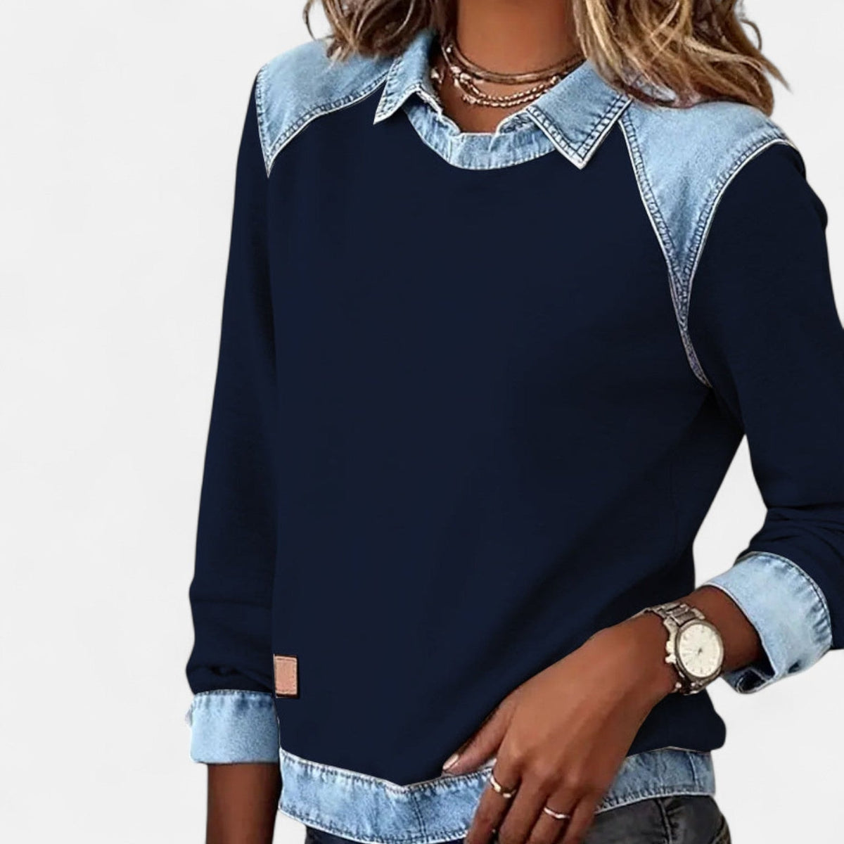 Front angled view of the navy long sleeve sweater with its contrasting pointed collar and blue sleeve cuffs.