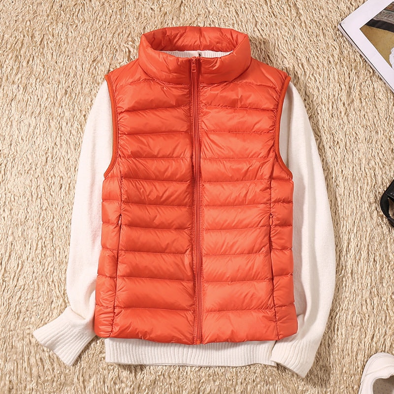 Orange quilted puffer vest layered over a white sweater, displaying the front zipper, high collar, and horizontal padding.