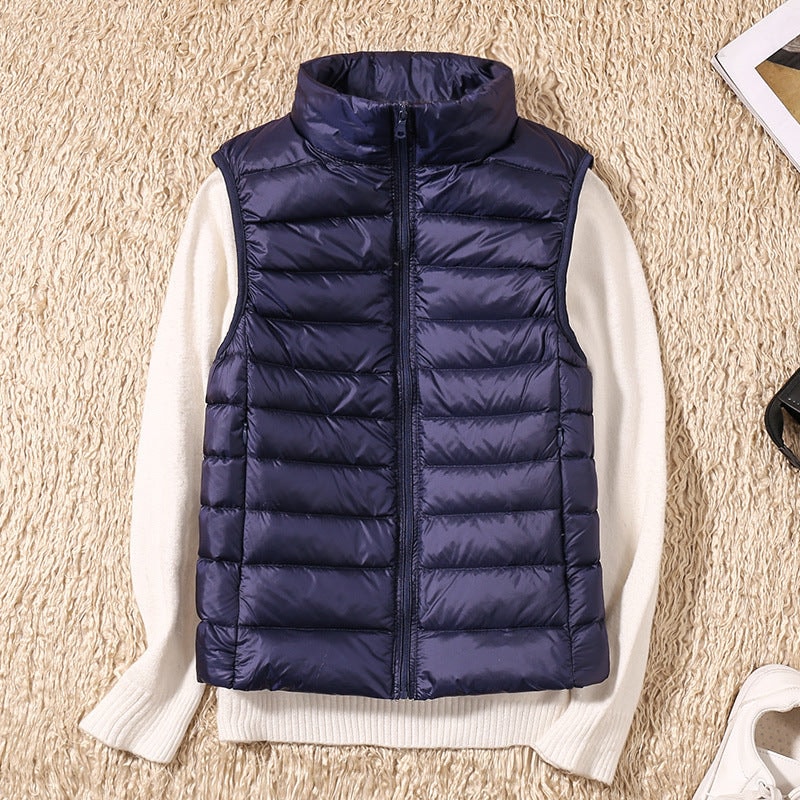 Deep navy quilted puffer vest over a white sweater, shown flat with its fitted sleeveless silhouette and side pockets.