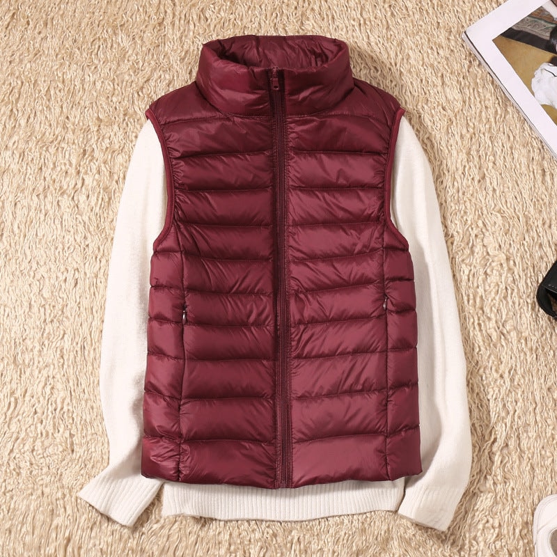 Burgundy quilted zip-up vest styled on a white sweater, showing the high collar and evenly spaced horizontal sections.