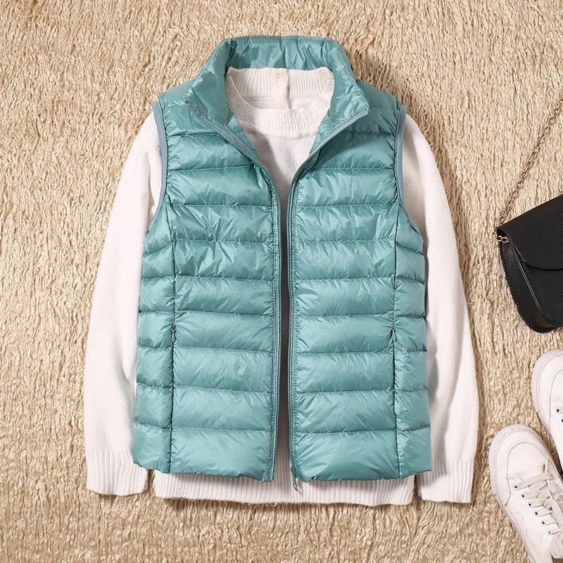 Aqua quilted vest layered over a white sweater with the front zipper open, revealing the contrasting top underneath.