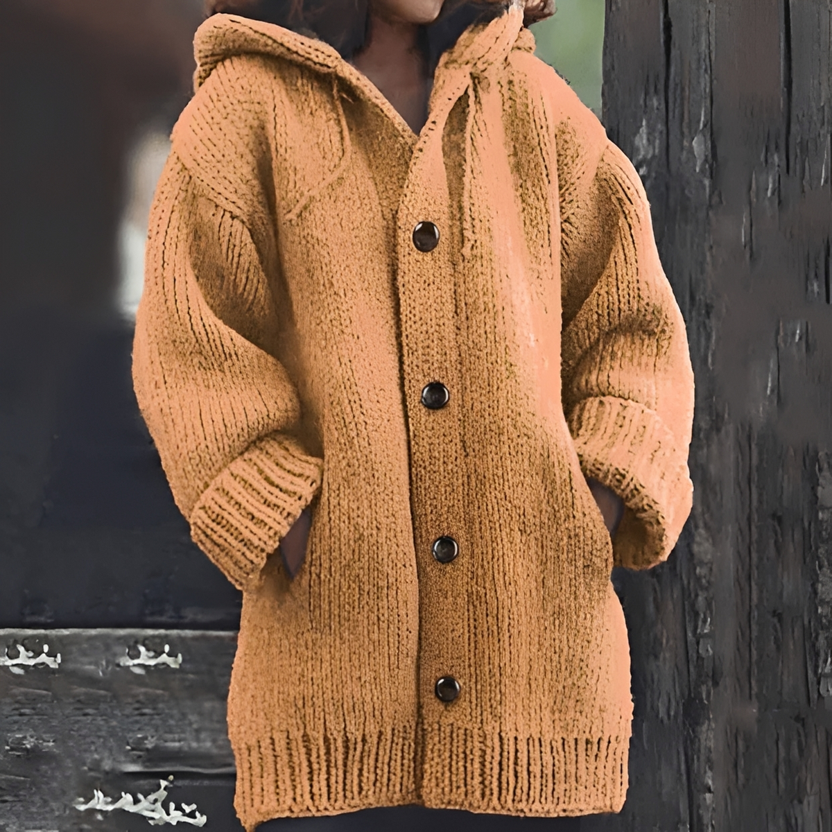 Warm tan hooded cardigan with a long fit, chunky textured knit, ribbed trim, and front patch pockets.